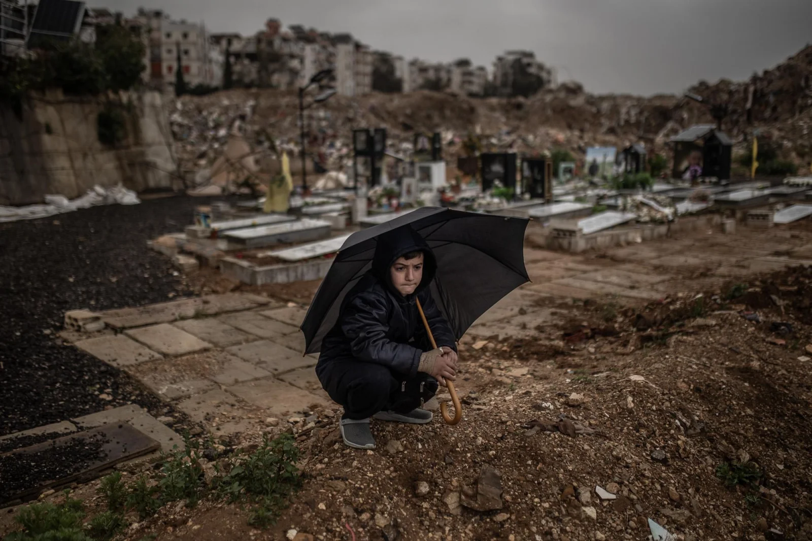 Un niño se resguarda de la lluvia bajo un paraguas durante el funeral de los periodistas Ali Shoeib, Fátima Ftouni y Mohamed Ftouni, asesinados en un bombardeo israelí en el sur del Líbano. Los reporteros murieron cuando un misil alcanzó su vehículo, claramente identificado con distintivos de prensa. Líbano