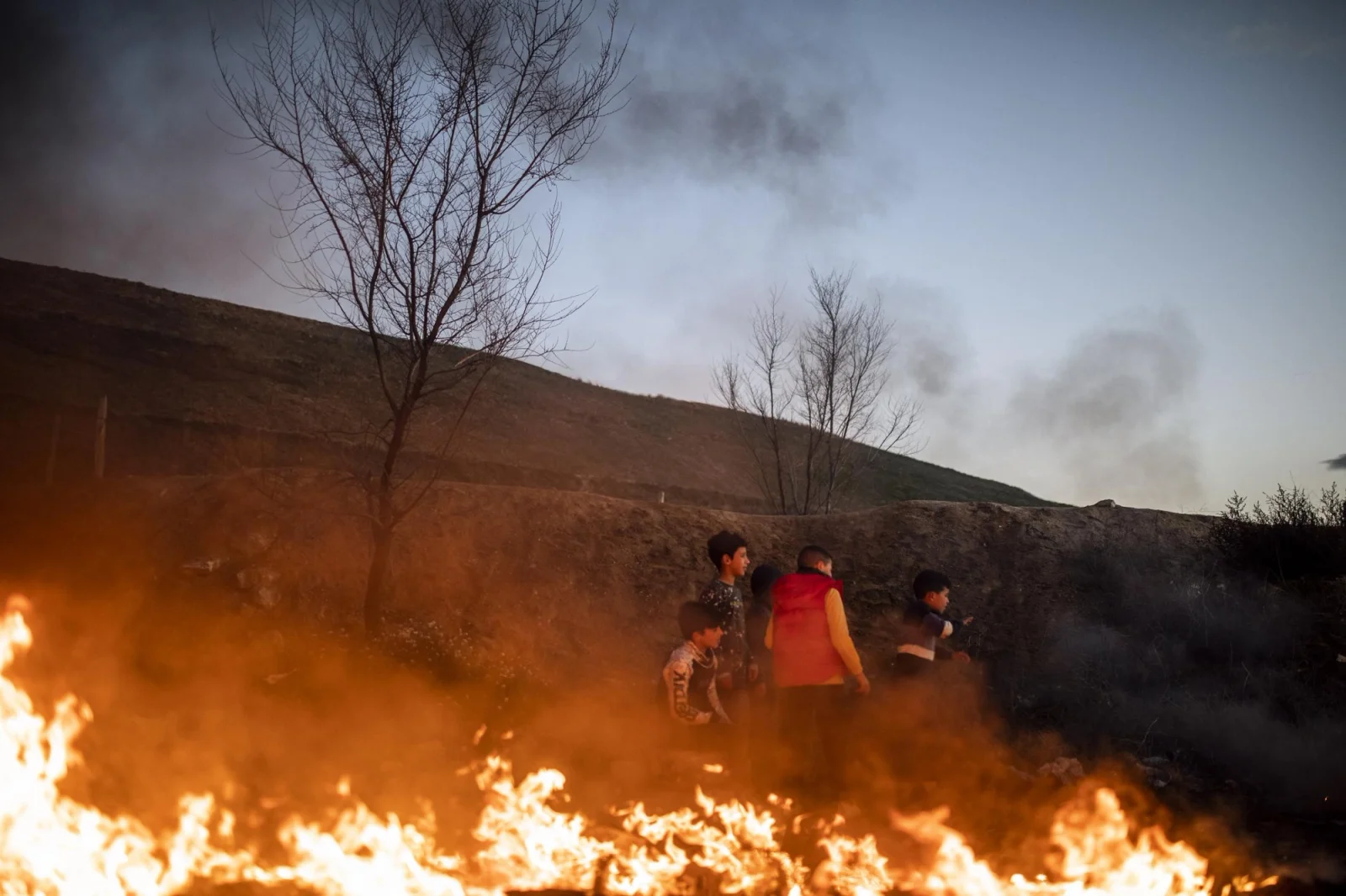 Varios niños juegan alrededor del fuego para poder calentarse en el Sector VI de la Cañada Real