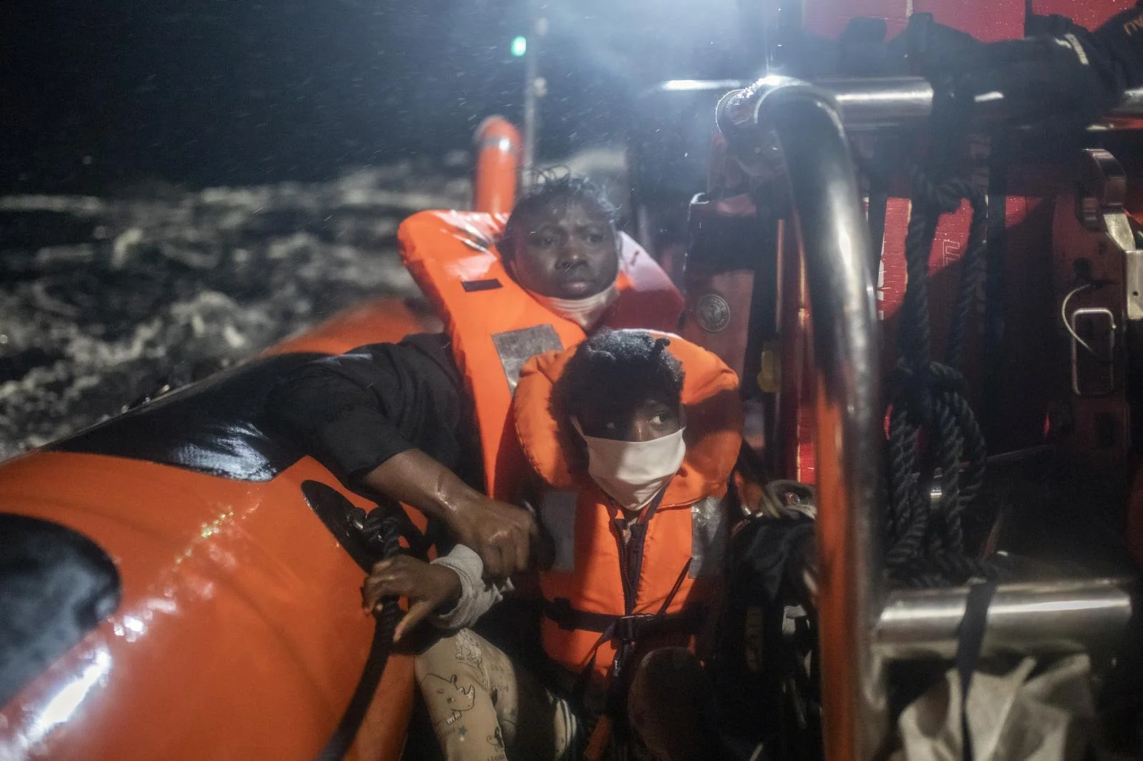 25-year-old Santa, originally from the Ivory Coast, can be seen clutching her 5-year-old daughter Timi's arm to prevent her from falling into the water, after being rescued from an overcrowded rubber boat Saturday, Feb. 13, 2021,