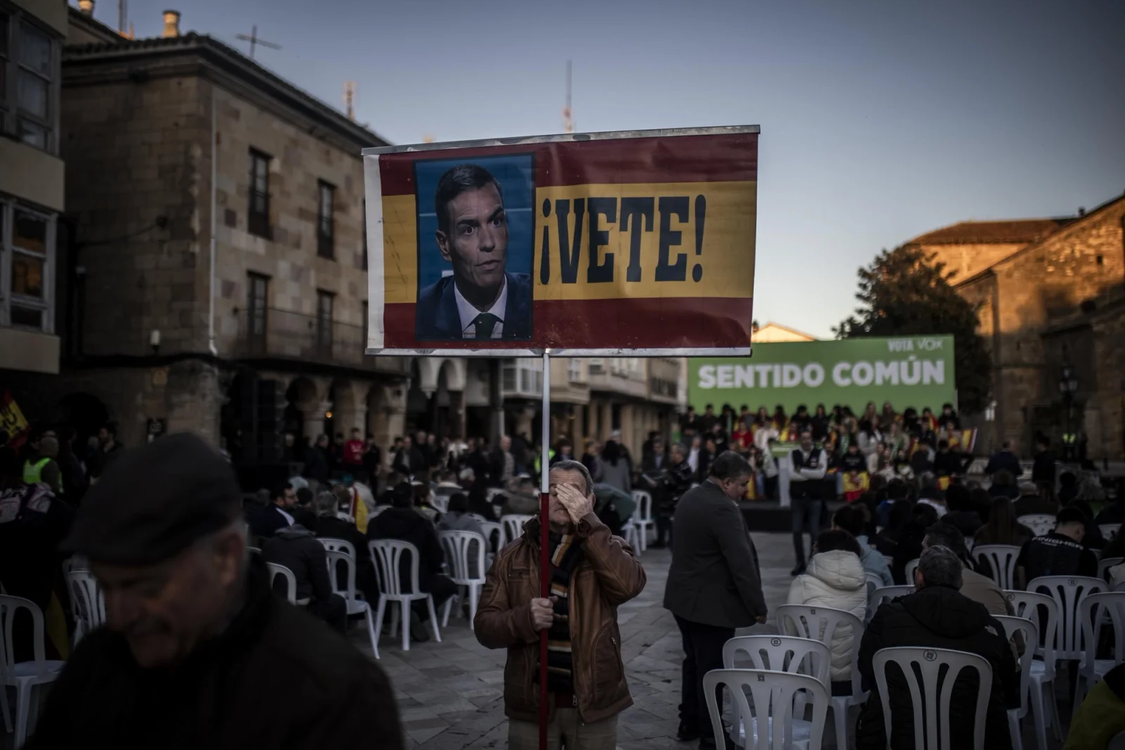 A man attending the Vox rally holds a sign criticizing