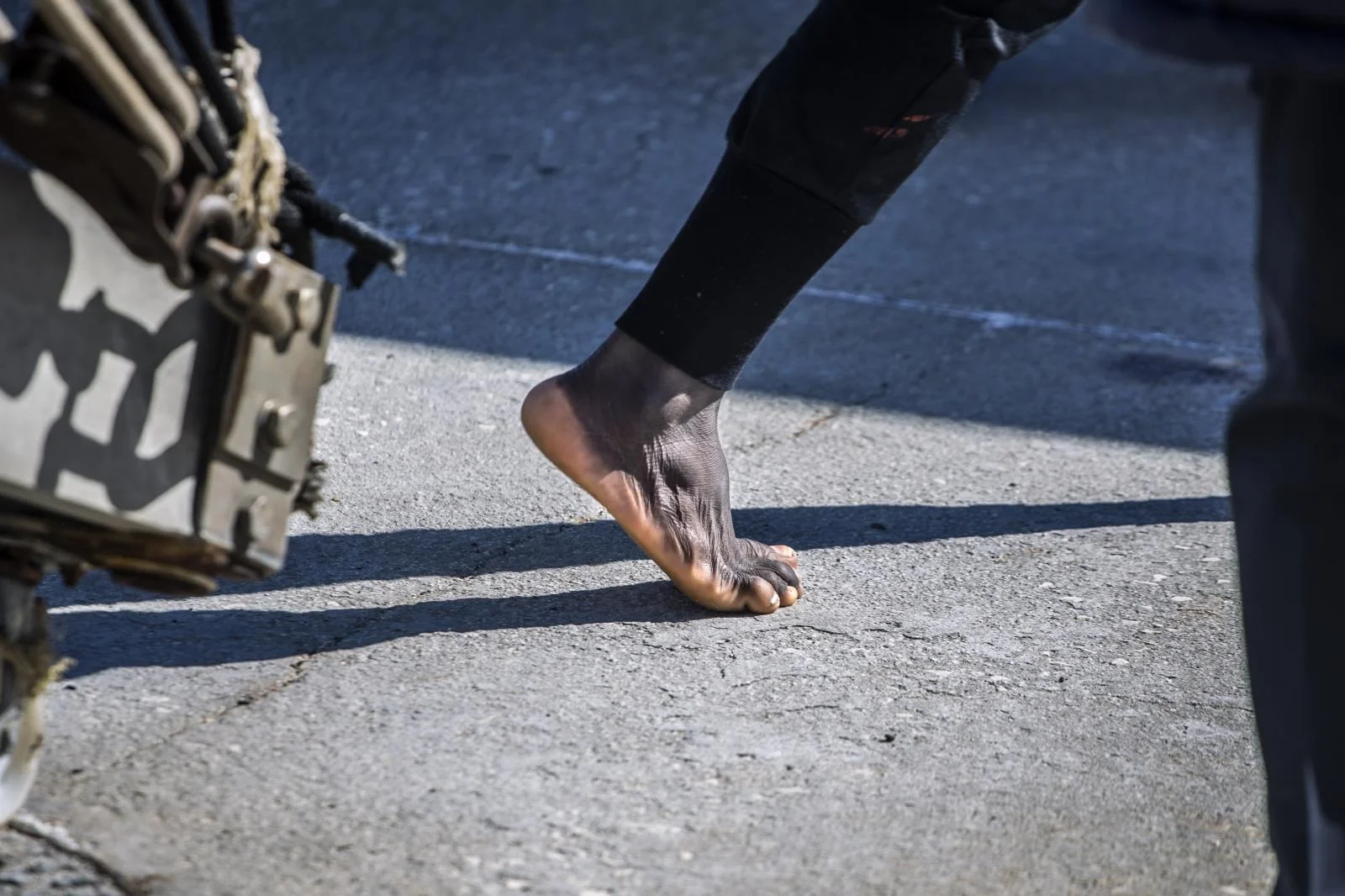 A migrant steps on the ground barefoot in the Italian port of Empedocles after being rescued by the Spanish NGO Open Arms in the Central Mediterranean Sea, Tuesday, Feb 16, 2021