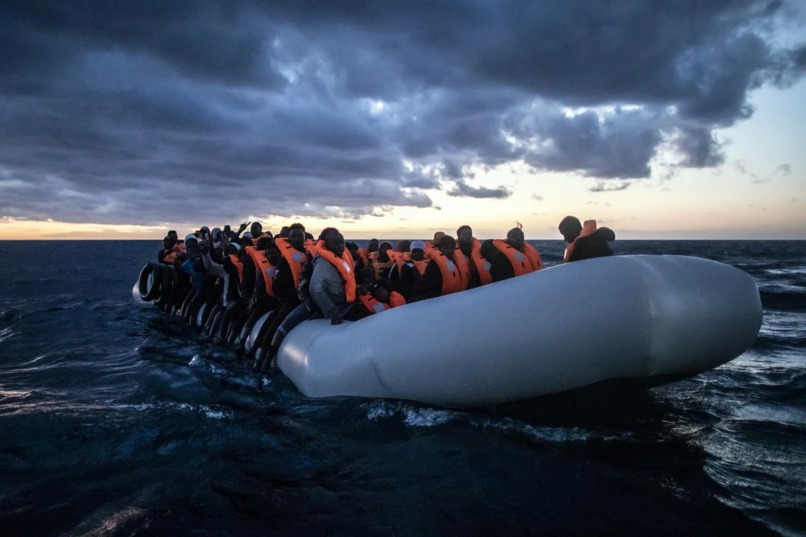 Migrants and refugees from different African nationalities wait for assistance aboard an overcrowded rubber boat, as aid workers of the Spanish NGO Open Arms approach them in the Mediterranean Sea, international waters, at 80 miles off the Libyan coast, Saturday Feb. 13, 2021.