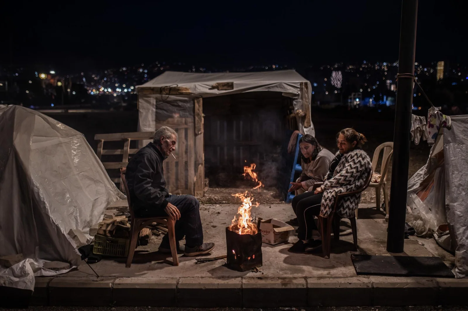 Un grupo de personas desplazadas de Dahie, al sur de Beirut, se agrupa alrededor de una hoguera frente a su tienda de campaña para combatir el frío. Líbano