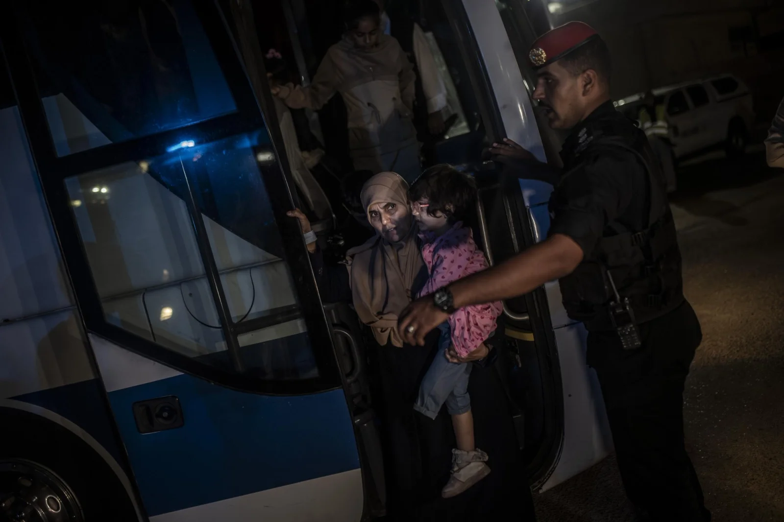 A Palestinian woman descends from a bus carrying her
