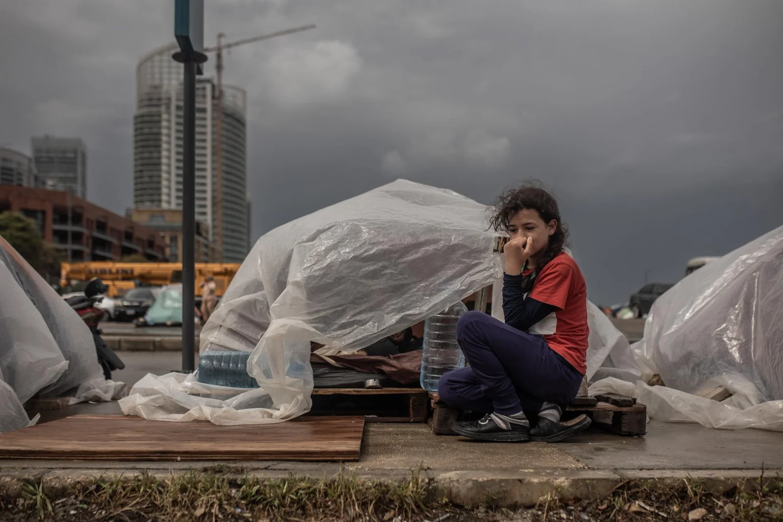 Yasmin, de 10 años, aguarda en un refugio improvisado con plásticos a orillas de una calle en Beirut. Como miles de desplazados por los bombardeos israelíes en el sur del Líbano y Dahie, espera poder regresar a su hogar. Líbano