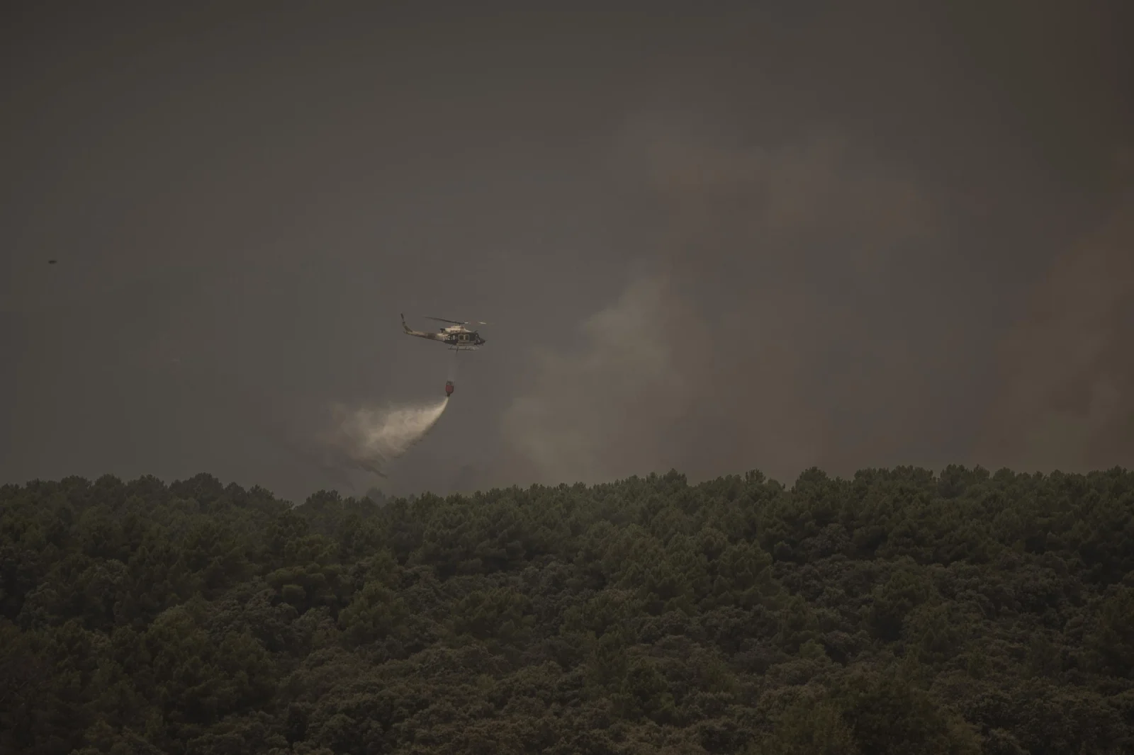A Military Emergency Unit (UME) helicopter drops water on