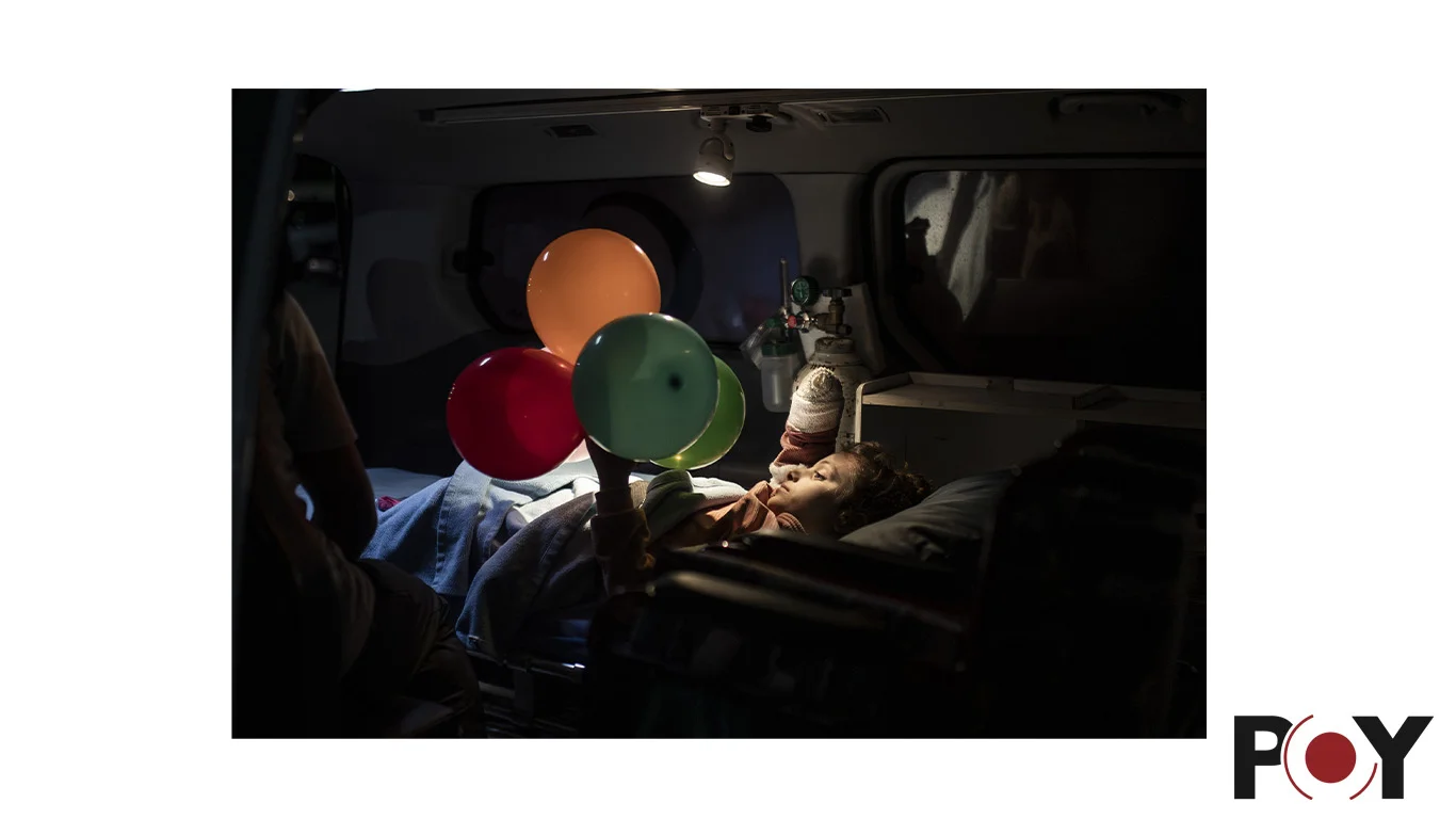 A child in an ambulance with balloons. Original photograph and POY recognition mark.