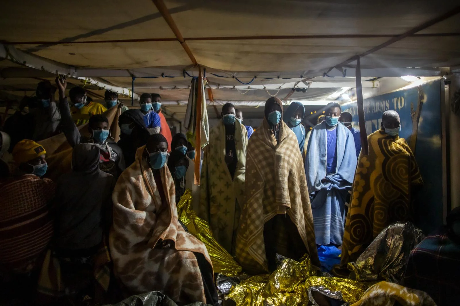 Migrants and refugees from from different African nationalities wearing blankets due to the cold awaits in the deck of the Spanish NGO Open Arms boat to disembark, Monday, Feb.15, 2021