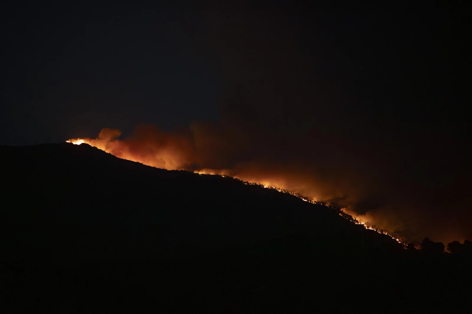 A line of fire burns along the mountain ridge during the