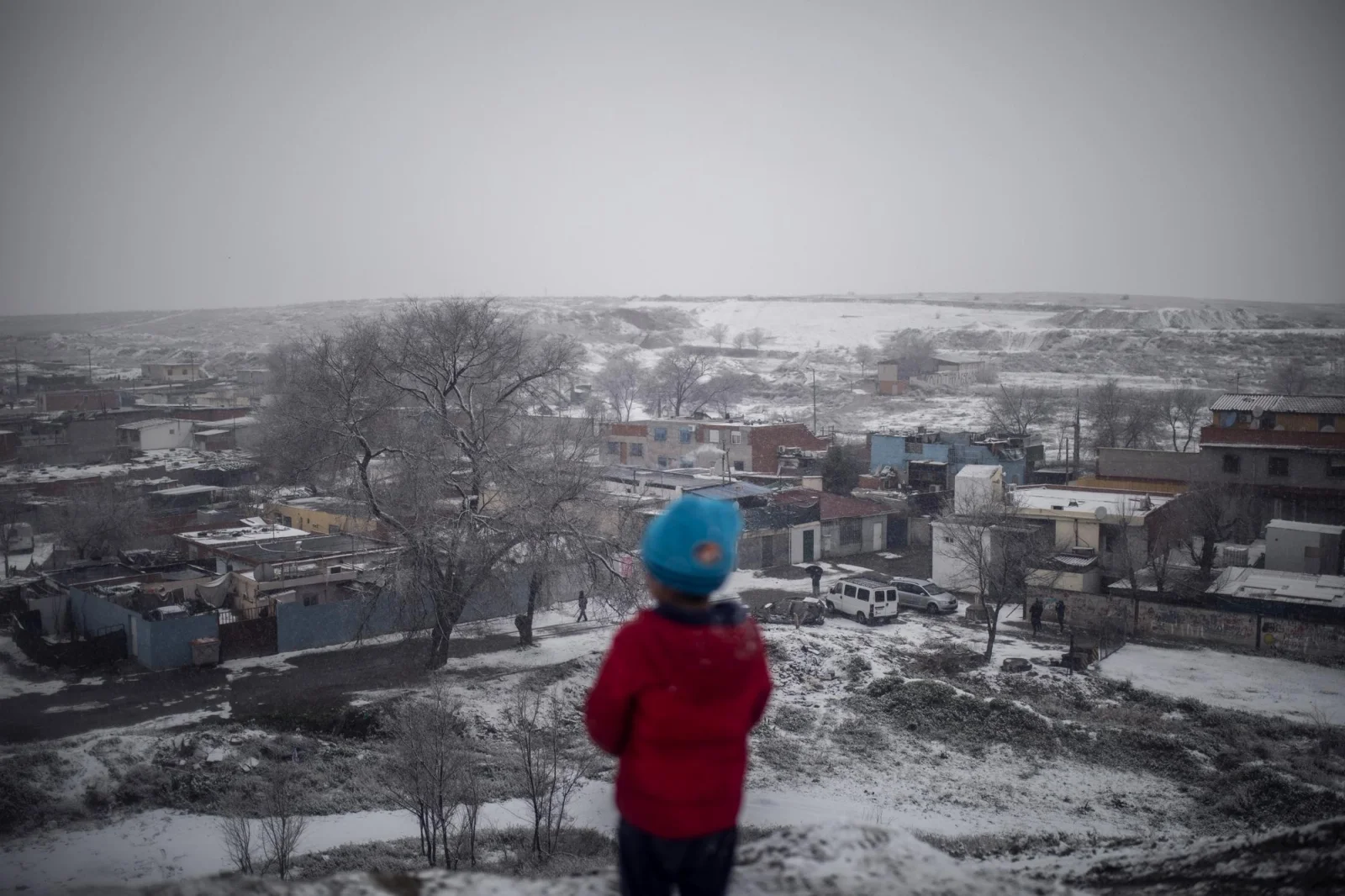 Un niño observa desde lo alto de una ladera el Sector VI de la Cañada Real durante la nevada